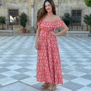 Mujer posando con vestido largo rojo coral con estampado geométrico y cuñas