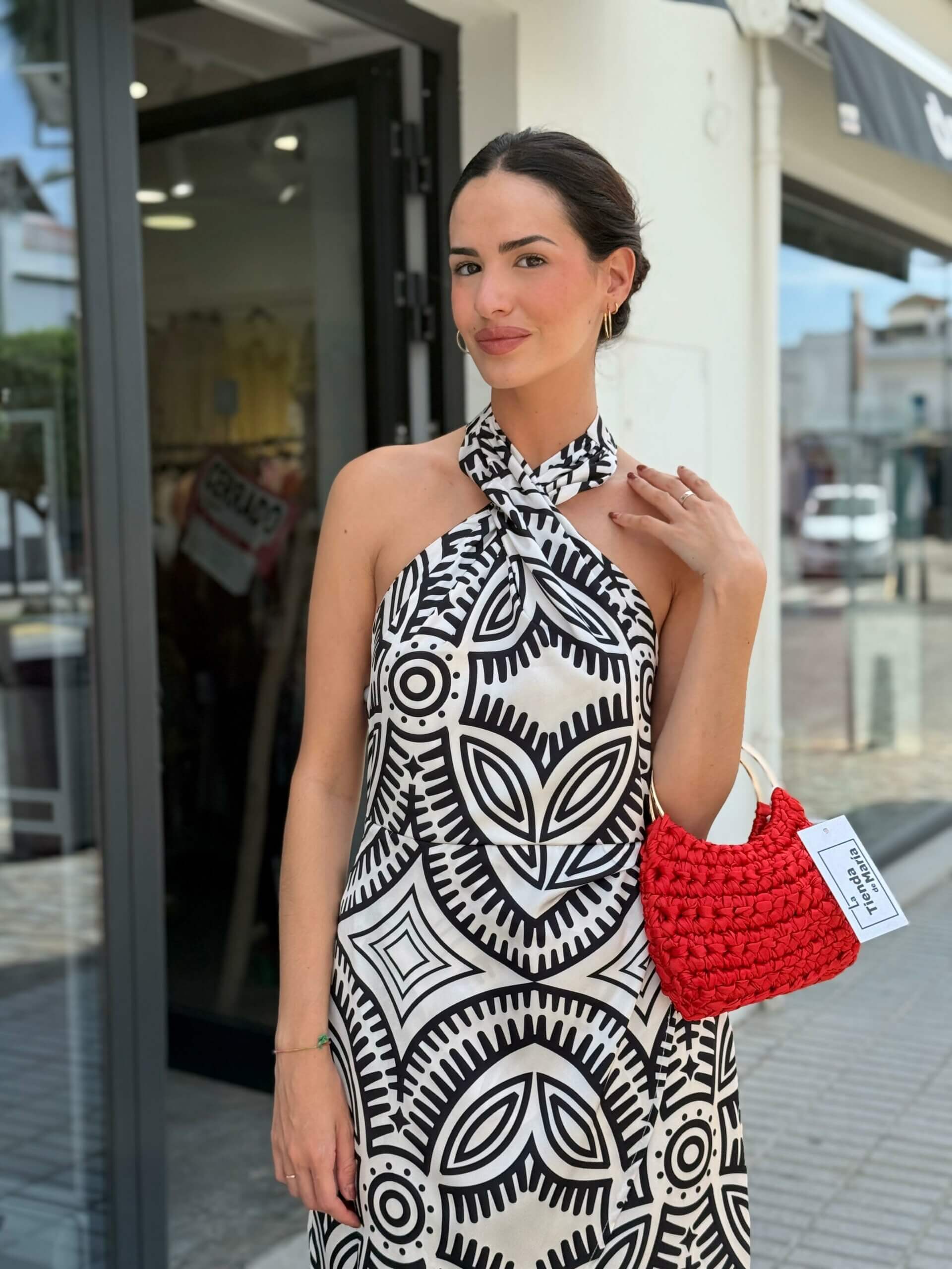 Mujer con vestido halter blanco y negro de estampado geométrico, vista frontal, escote anudado al cuello