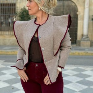Mujer con chaqueta beige estructurada y ribetes burdeos, cierre de botones
