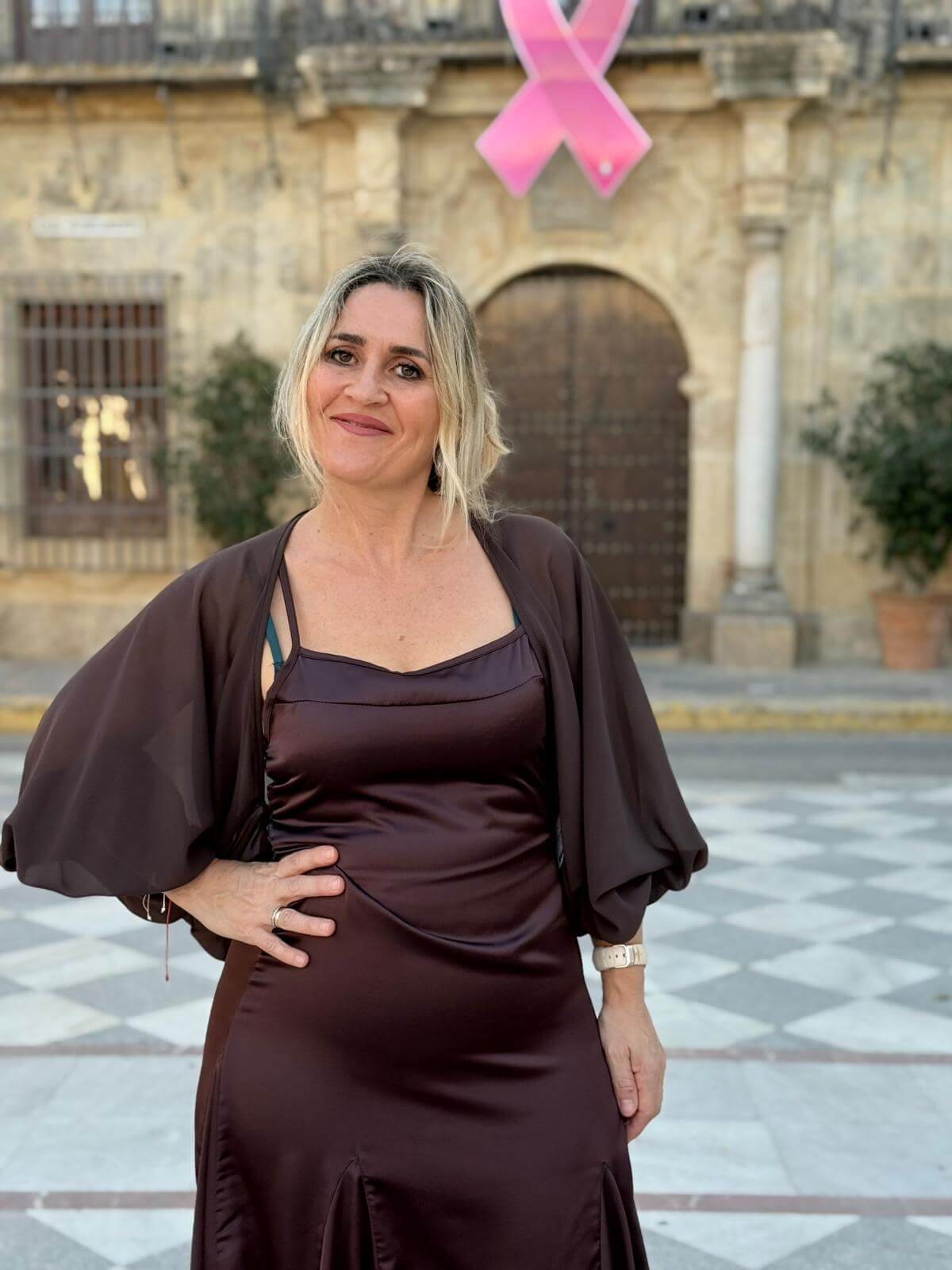 Mujer con vestido satinado color chocolate y capa de gasa, escote recto