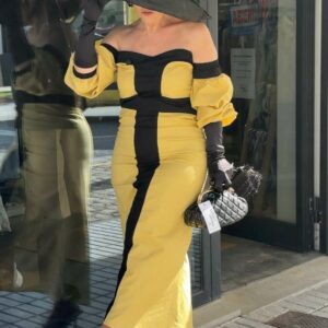 Mujer con vestido midi mostaza y negro con escote palabra de honor y manga abullonada